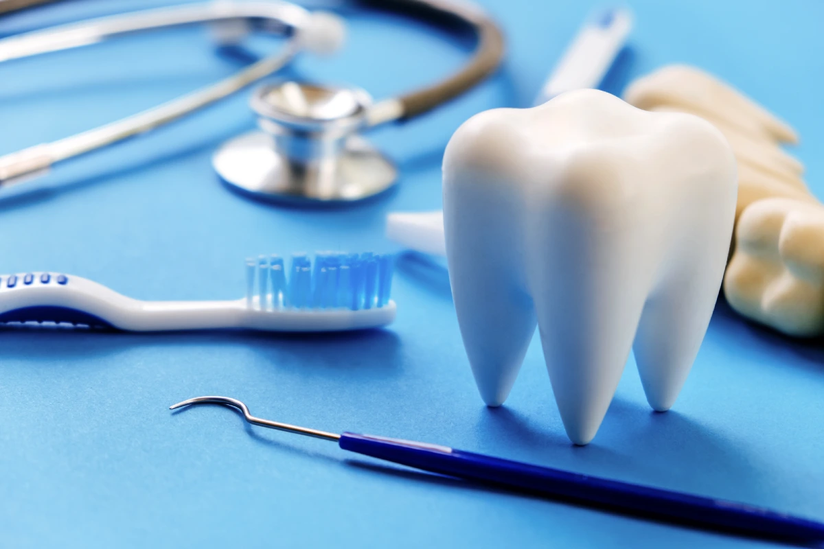 Dental tools and a model tooth on a blue surface.