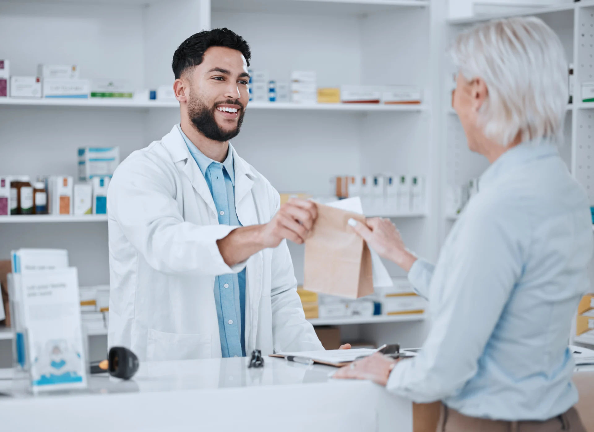 A pharmacist handing out a paper bag to a customer.
