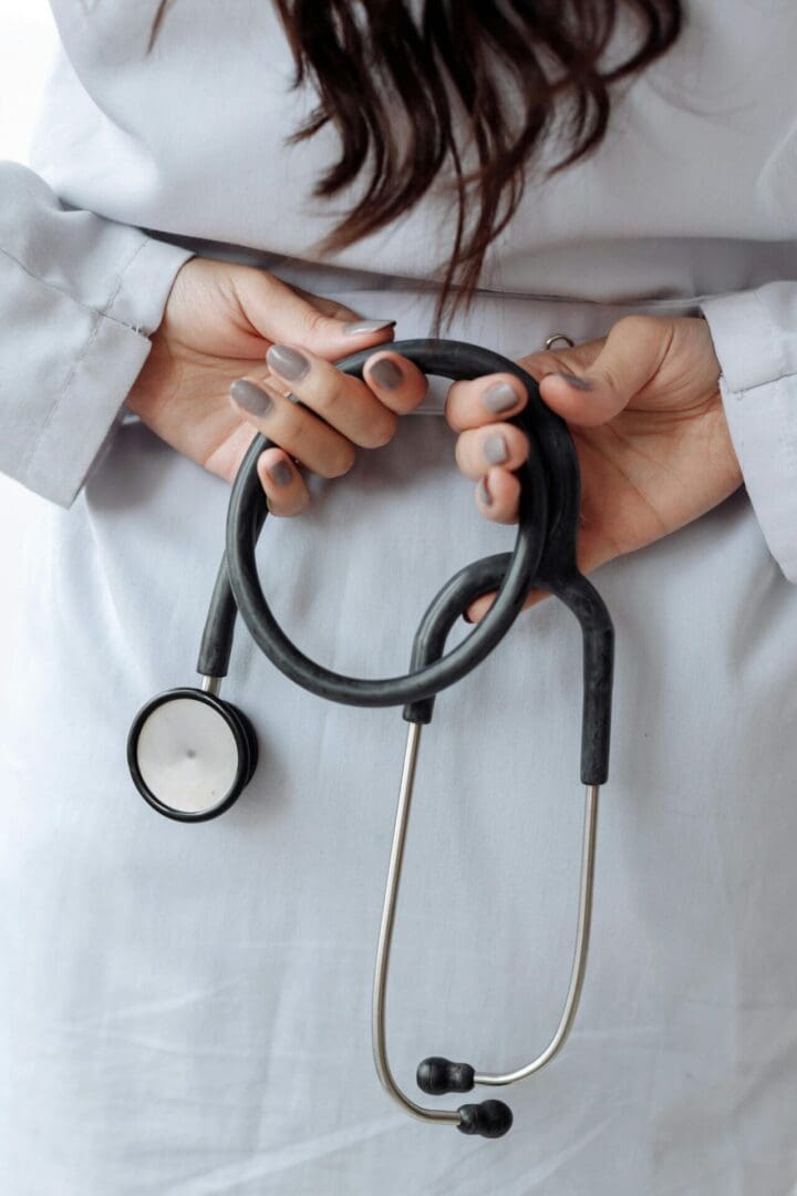 A healthcare professional holding a stethoscope behind their back.