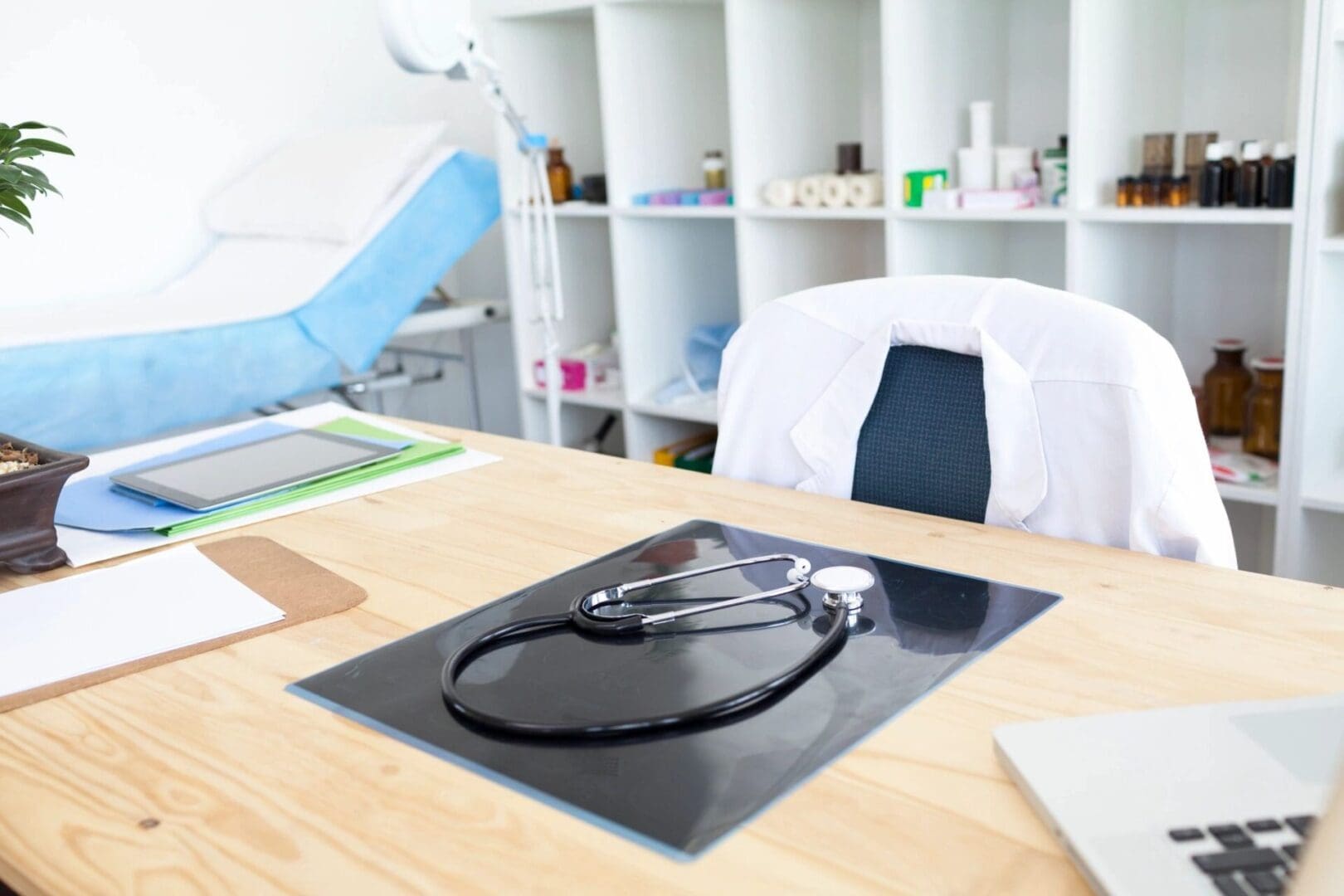 A stethoscope on a table and a white coat on a chair.