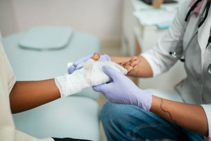 A healthcare worker holding a patient's bandaged hand gently.