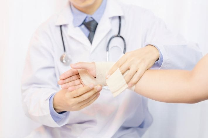 Doctor wrapping a patient's wrist with a bandage.