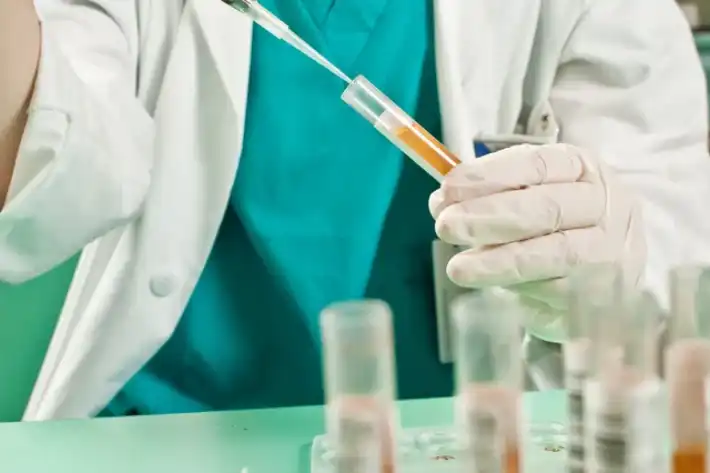 Scientist drawing liquid from a test tube in a lab.