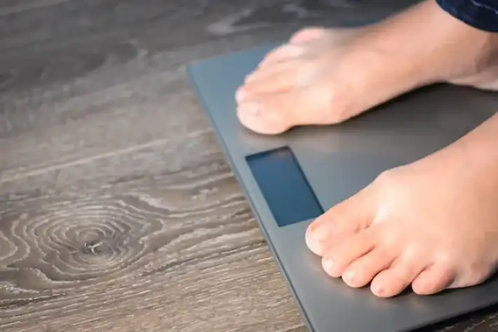 Person standing barefoot on a digital bathroom scale.