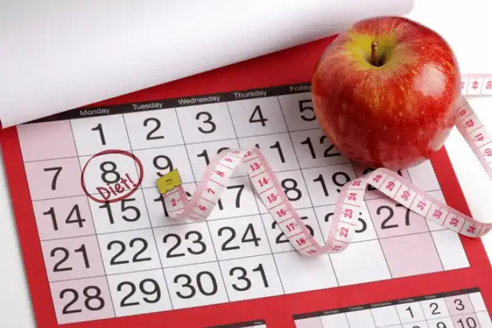 Calendar marked for ovulation with an apple and measuring tape nearby.