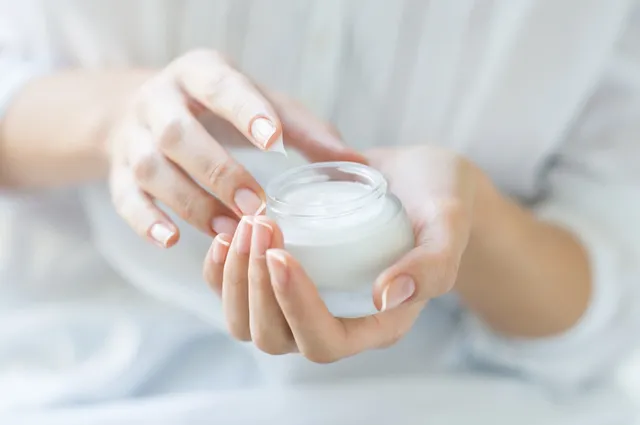 Woman holding a jar of cream with manicured nails.