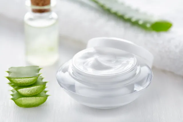 A glass bowl filled with white aloe vera gel cream.