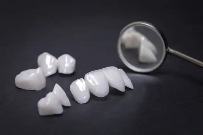 Dental crowns and a mirror on a black surface.
